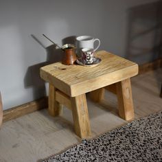 a small wooden table with two cups on it