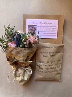 a bouquet of flowers sitting on top of a table next to a piece of paper