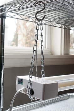 a close up of a metal shelf with wires attached to it and a window in the background