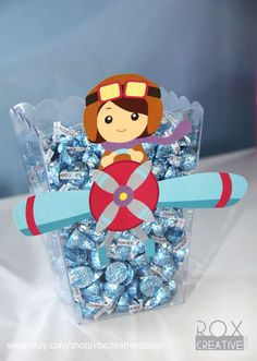 a box filled with blue candies sitting on top of a white table next to an airplane