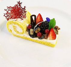 a piece of cake on a plate with berries and other fruit toppings around it