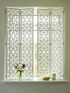 a vase with flowers sitting on top of a window sill next to a white tiled wall