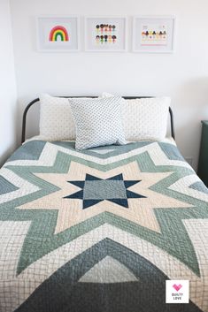 a bed with two pictures on the wall above it and a quilted bedspread