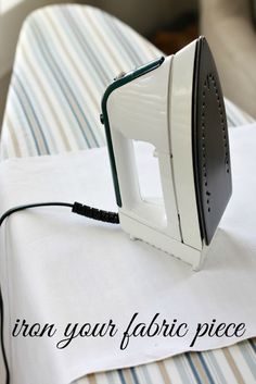 an iron on top of a bed with the words iron your fabric piece below it