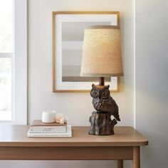 an owl lamp sitting on top of a table next to a book and coffee cup