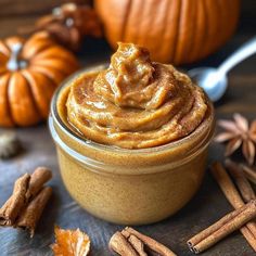 a glass jar filled with pumpkin butter surrounded by cinnamon sticks