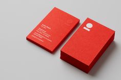 two red business cards sitting side by side on top of a gray surface with white circles