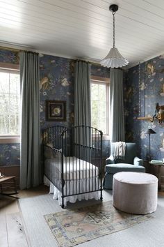 a bedroom with floral wallpaper and a metal crib in the corner next to a window