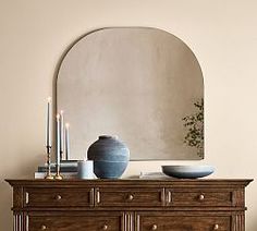 a wooden dresser topped with a blue vase and two white bowls sitting on top of it