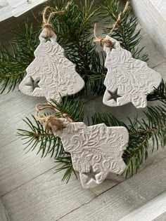 three white ceramic ornaments hanging from a pine tree