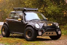 a black car parked on the side of a road in front of trees and bushes