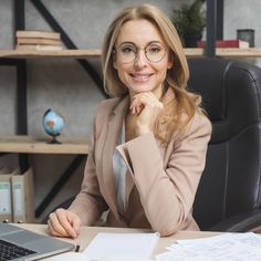 a woman sitting at a desk in front of a laptop computer