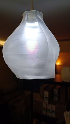 a white light hanging from a ceiling in a room with boxes on the floor behind it