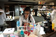 a woman working in a lab with lots of test tubes and flasks on the counter