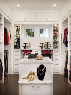 a white closet filled with lots of clothes and jewelry on display next to a window