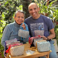 two people sitting next to each other at a table with purses on top of it