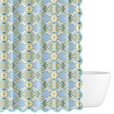 a blue and white shower curtain with flowers on the bottom, in front of a bowl