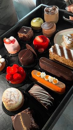 there are many different desserts in the tray on the table, including cakes and cupcakes