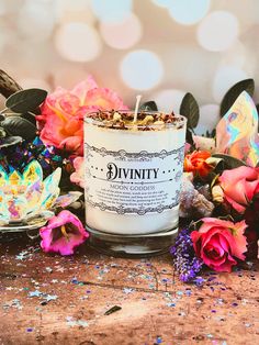 a white candle sitting on top of a wooden table surrounded by flowers and confetti