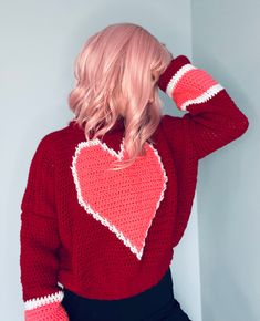 a woman with pink hair wearing a red heart sweater