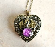 "Dragon music box pendant. This heart shaped music box pendant is inspired by the gorgeous music box pendants of era's gone by. Music box is pill box size, please look at the dimensions for exact size. A perfect heart locket in bronze has been adorned with bronze filigree, a bronze dragon with a fused glass dichroic glass cabochon in purples, pink and a touch of gold and blue. Glass cabochon may vary from photographs. Dragon and filigree have been covered in a clear resin to give a glass like fi Antique Dragon Design Jewelry Gift, Antique Dragon Design Jewelry For Gift, Vintage Dragon Design Jewelry Gift, Vintage Dragon Design Jewelry For Gifts, Vintage Jewelry With Dragon Design Gift, Vintage Jewelry With Dragon Design For Gift, Music Box Locket, Heart Shaped Locket, Perfect Heart