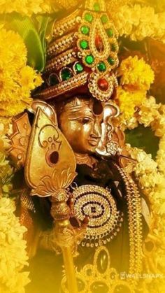 an idol is surrounded by yellow flowers and greenery in the foreground, as well as a golden background