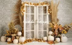 an old window surrounded by fall foliage and pumpkins is displayed in front of a brick wall