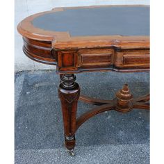 an old wooden table with black top and brown wood trimmings on the edges