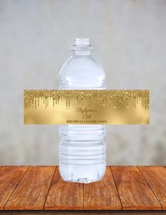 a water bottle with a gold foil label on it sitting on top of a wooden table