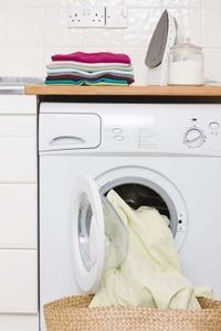 a white washer sitting inside of a kitchen next to a wooden counter top with a cloth dispenser in it