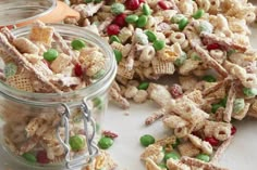 a pile of cereal mix next to a glass jar filled with candy canes and sprinkles