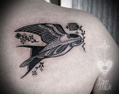 a bird tattoo on the back of a man's shoulder