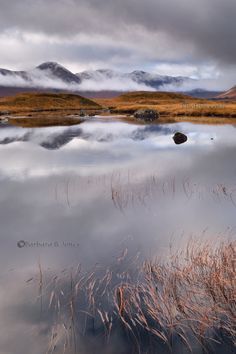 an image of a lake that is in the middle of some land with mountains in the background