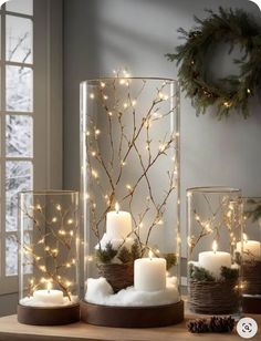 lighted candles and branches in glass containers on a table