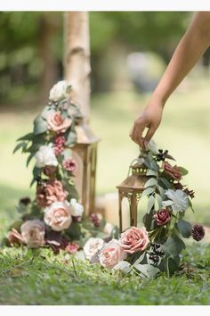 a person placing flowers on the ground next to a lamp and some grass with trees in the background