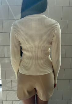 Your classic ribbed knit sweater with a twist. This beautiful off-white garment is cozy and stylish. The unique twist front detail adds a fashionable element to a timeless sweater, making it trendy and comfortable. It is a versatile choice for various occasions, from casual outings to dressier events. Fabric content: 50% rayon, 25% polyester, 22% nylon Washing instructions: dry clean only Imported Model: 5'3" wearing size extra small. Chic Textured Knit Everyday Sweater, Fitted Neutral Knit Top For Fall, Chic Cream Sweater, White Ribbed Knit Top For Layering, White Ribbed Knit Top For Work, Chic Ribbed Sweater For Work, Cream Ribbed Knit Top For Fall, Ribbed Cream Knit Top For Fall, Chic White Sweater With Ribbed Neckline