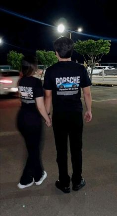 two people standing in an empty parking lot at night, one holding the other's hand