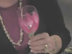 a close up of a person holding a wine glass with pink liquid in the middle