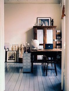 an open door leading to a desk with a laptop on it and pictures hanging up against the wall