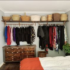 an organized closet with clothes and baskets hanging on the wall, next to a bed