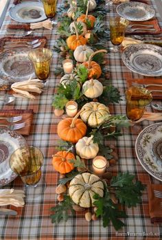 a long table is set with pumpkins and gourds