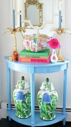 a blue table with two vases on it and a mirror in the corner behind it