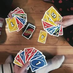 several people are playing cards on a wooden table with one person's leg in the air