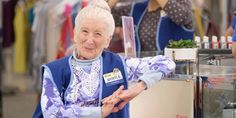 an elderly woman standing in front of a counter