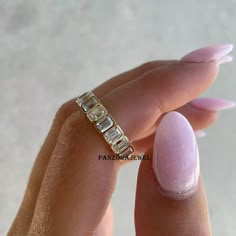 a woman's hand holding a ring with three baguets on it,