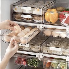 a refrigerator door is open with food in the drawer and one hand reaching for an egg