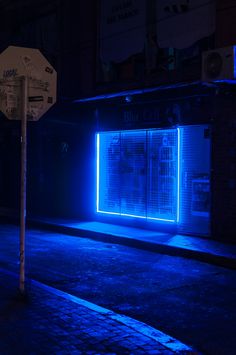 a stop sign sitting on the side of a road next to a blue lit building