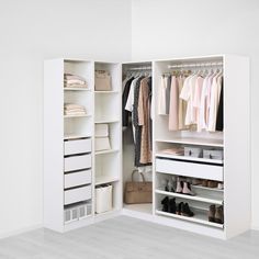 an open closet with clothes, shoes and handbags on shelves next to a white wall