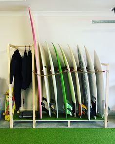 several surfboards are lined up against a wall in a room with green carpeting