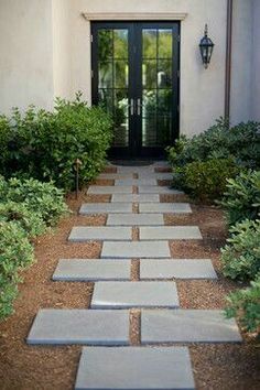 an entry way to a home with stone walkways and plants in front of it